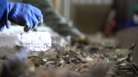 cinematic shot of men wearing gloves sorted shredded milk cartons on conveyor belt in recycling factory