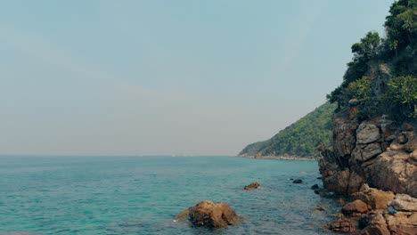 Braune-Felsen-Am-Strand,-Azurblaue-Ozeanküste,-Bedeckt-Mit-Dschungel