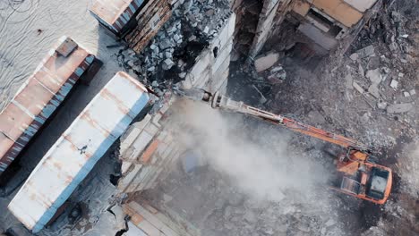 destroying old concrete building using mechanical arm of bulldozer on construction site. aerial view