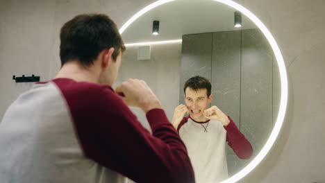 man flossing in bathroom mirror