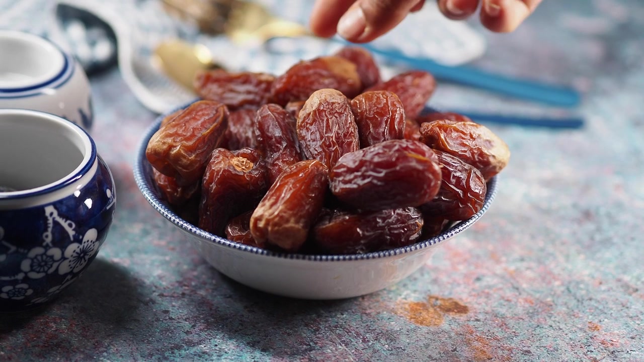 Hand Picking a Sweet Date from a Bowl