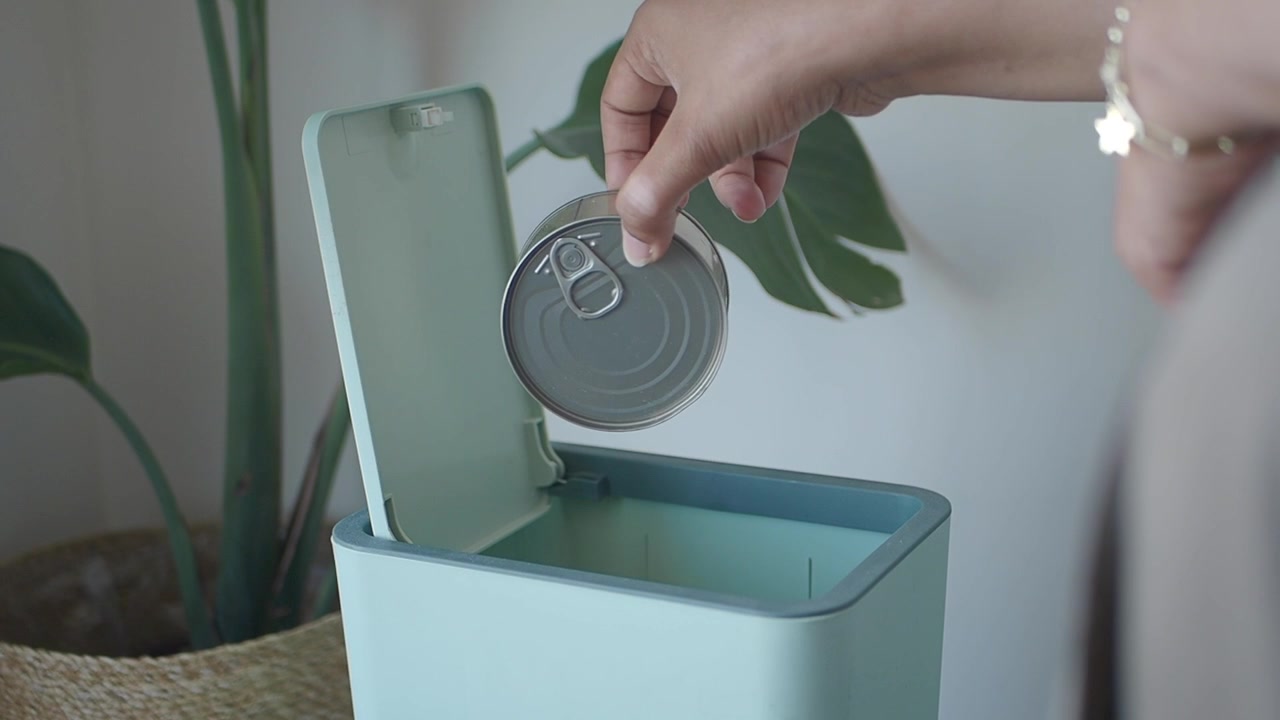Person Disposing of Metal Can in Modern Trash Bin
