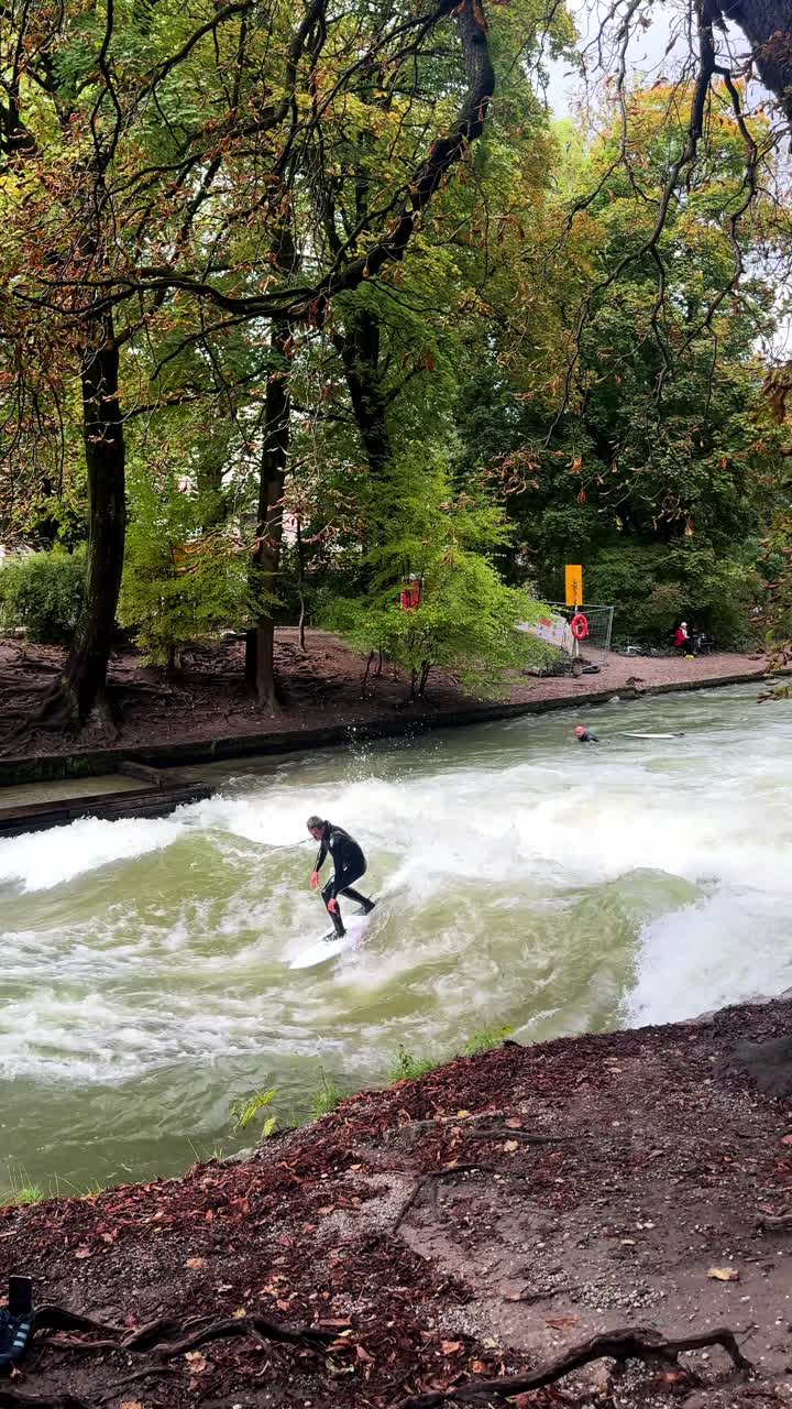 Våddragt surfere River Surfing morgen Eisbachwelle Eisbach Isar River München Tyskland vertikal turistattraktion gadebillede Efterår Englischer Garten stående bølge vand action sports stunts pan