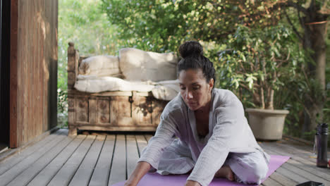 focused biracial woman practicing yoga on terrace, slow motion