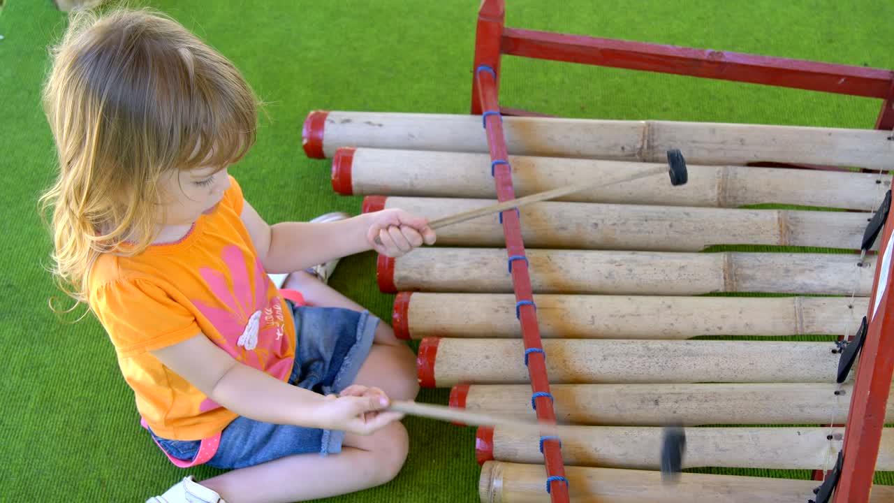 una niña juega con palos especiales en instrumentos tradicionales indonesios