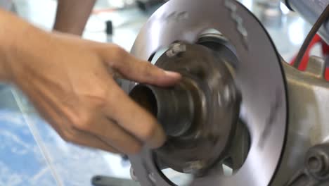 close-up footage of the technician working on motorcycle brake caliper cleaning process