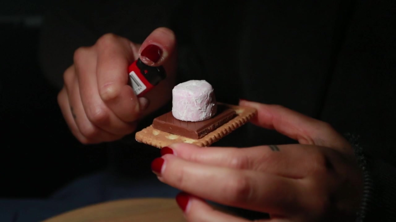 Ein Marshmallow wird nachts mit einem Feuerzeug angezündet.