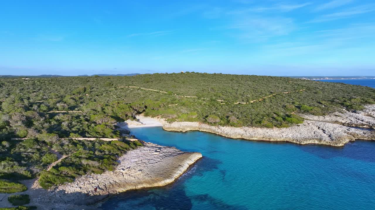 Luftfoto af Son Saura Jomfrustrand på en dag med klar blå himmel på Menorca, Spanien, sporende vidvinkeloptagelse