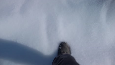 a fpv shoot of a pair of boots walking on snow