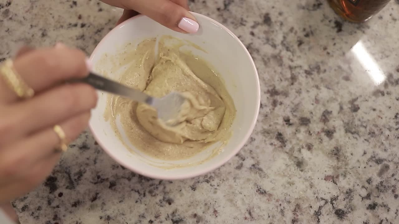 las manos de las mujeres baten los ingredientes para la vista cerrada de la mesa de la cocina