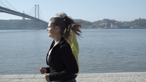 sporty runners exercising together near lake in sunny day