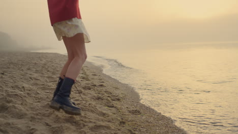 Fashionable-girl-in-boots-jumping-on-beach.-Young-woman-feet-turning-around