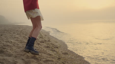 chica de moda con botas saltando en la playa. mujer joven pies dando la vuelta