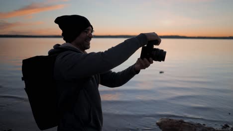 man taking photo at sunset on a lake