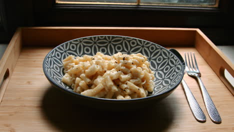 focus pull to macaroni cheese meal with spoon and fork on wooden tray