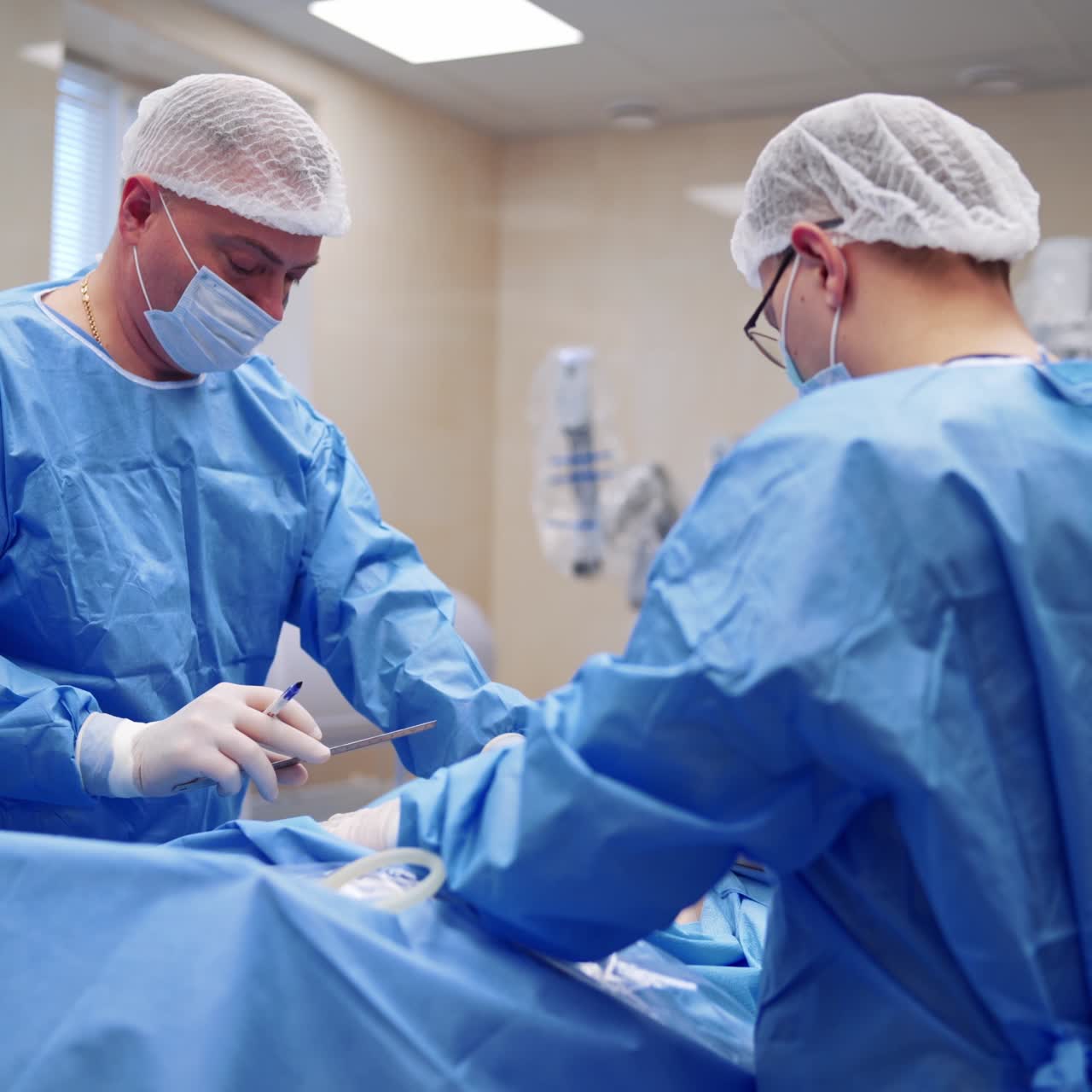 Shot in the operating room. Surgeons use medical instruments during operation. Doctors in protective uniform and masks perform surgery in clinic.