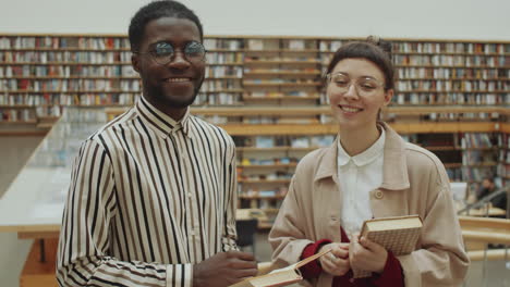 retrato de un hombre y una mujer multiétnicos alegres en la biblioteca