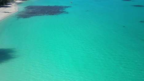 A-drone-flies-over-unbelievably-blue-water-with-a-red-boat-at-Port-Olry-on-the-island-of-Espiritu-Santo