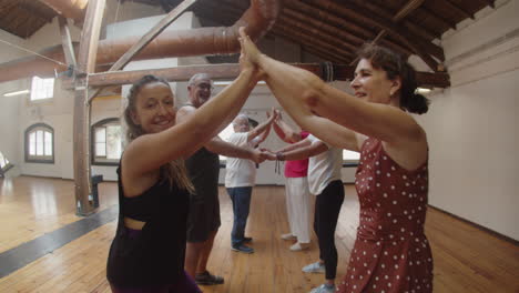 people in pairs standing against each other and dancing in dance studio