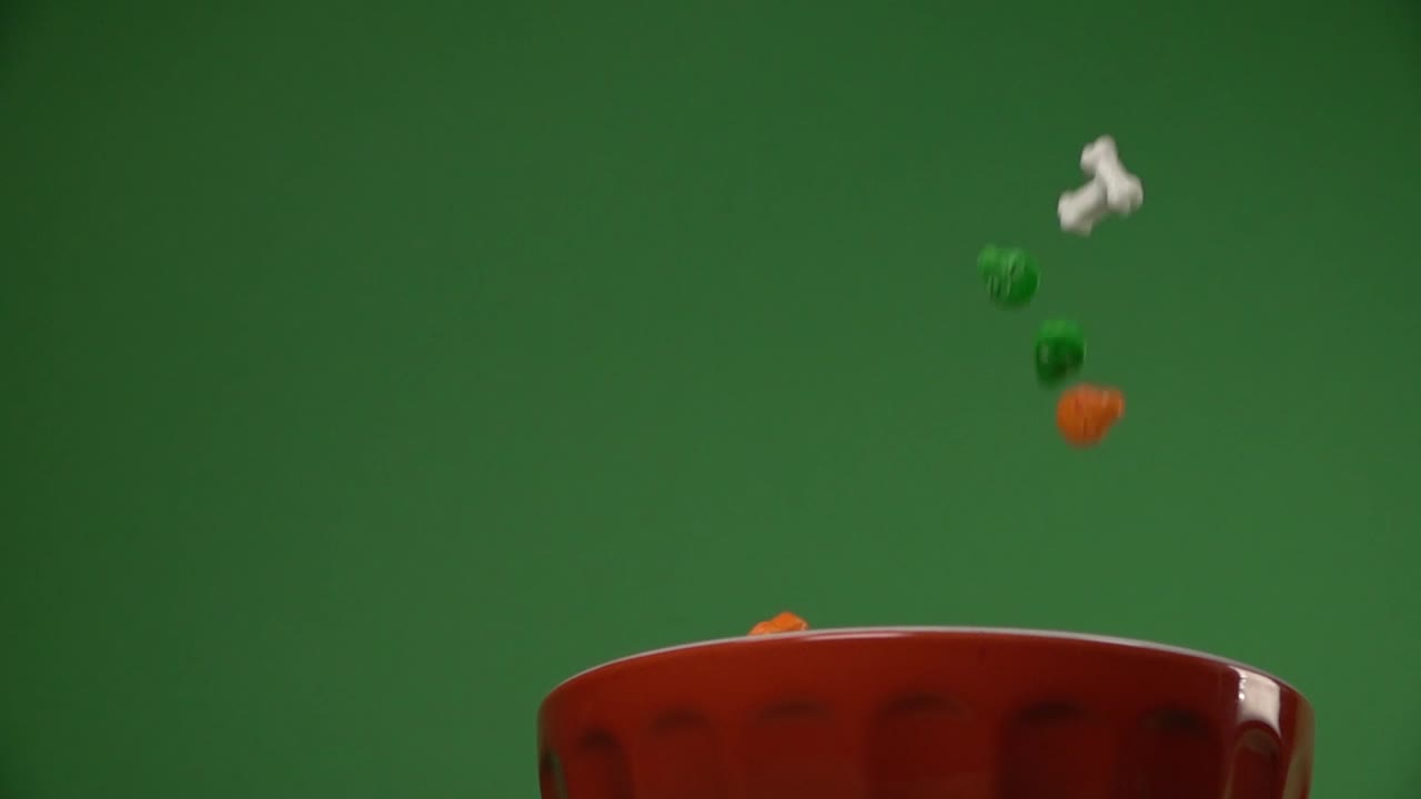 vista baja de huesos y dulces en forma de calaveras cayendo sobre un plato