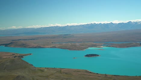 cámara lenta - hermoso glaciar azul lago tekapo, nueva zelanda desde un avión de vuelo panorámico con montañas en el fondo