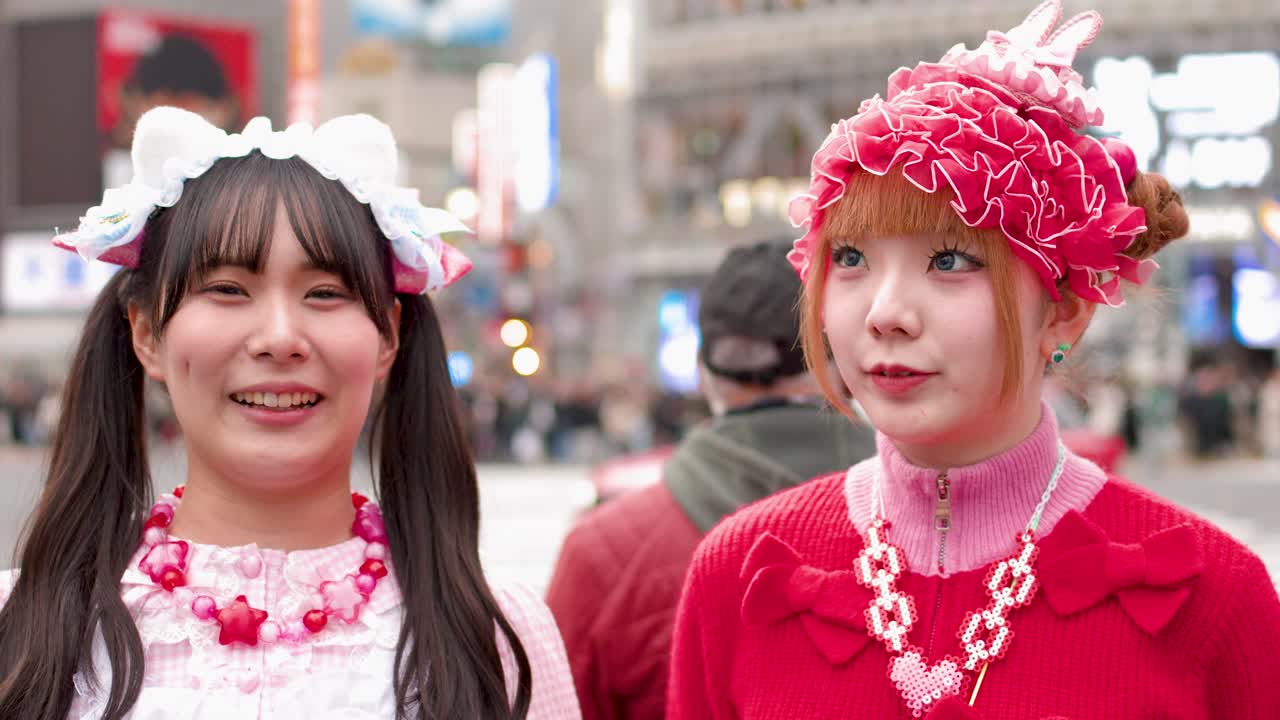 兩位身穿鮮豔粉紅色Decora街頭時尚的女士在東京澀谷十字路口開懷大笑