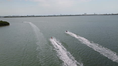 Vista-Aérea-Siguiendo-Motos-Acuáticas-En-La-Costa-De-Miami,-Día-Soleado-En-EE.UU.