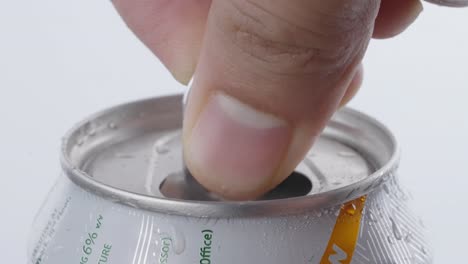 lata de cerveza abierta por el pulgar de una persona