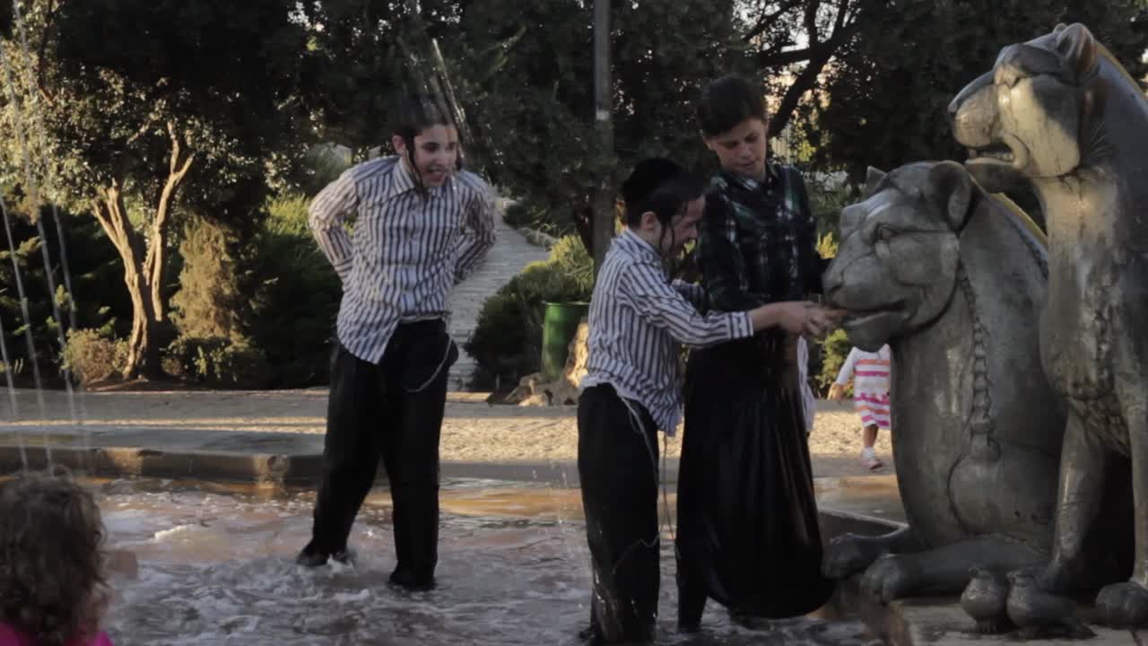 Orthodox Jewish kids playing in a fountain