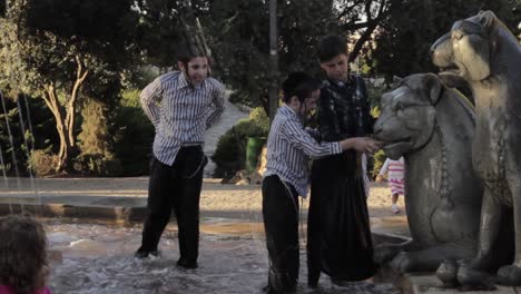 orthodox jewish kids playing in a fountain