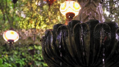 Hermosa-Fuente-Goteando-Agua-Con-Hermosas-Luces-De-Fondo-En-Los-Alrededores-Del-Jardín-Al-Aire-Libre