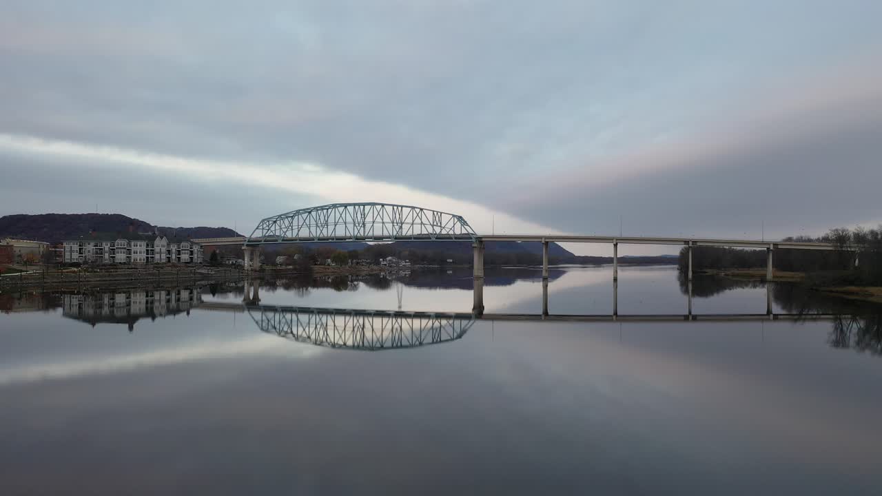 새벽이나 저녁에 강을 가로지르는 평화로운 다리 반사