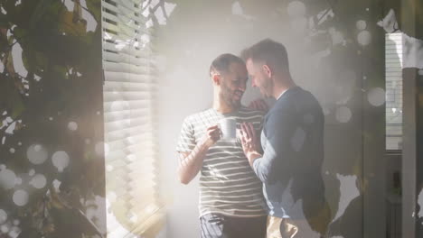 animation of leaves over diverse male couple embracing and drinking coffee