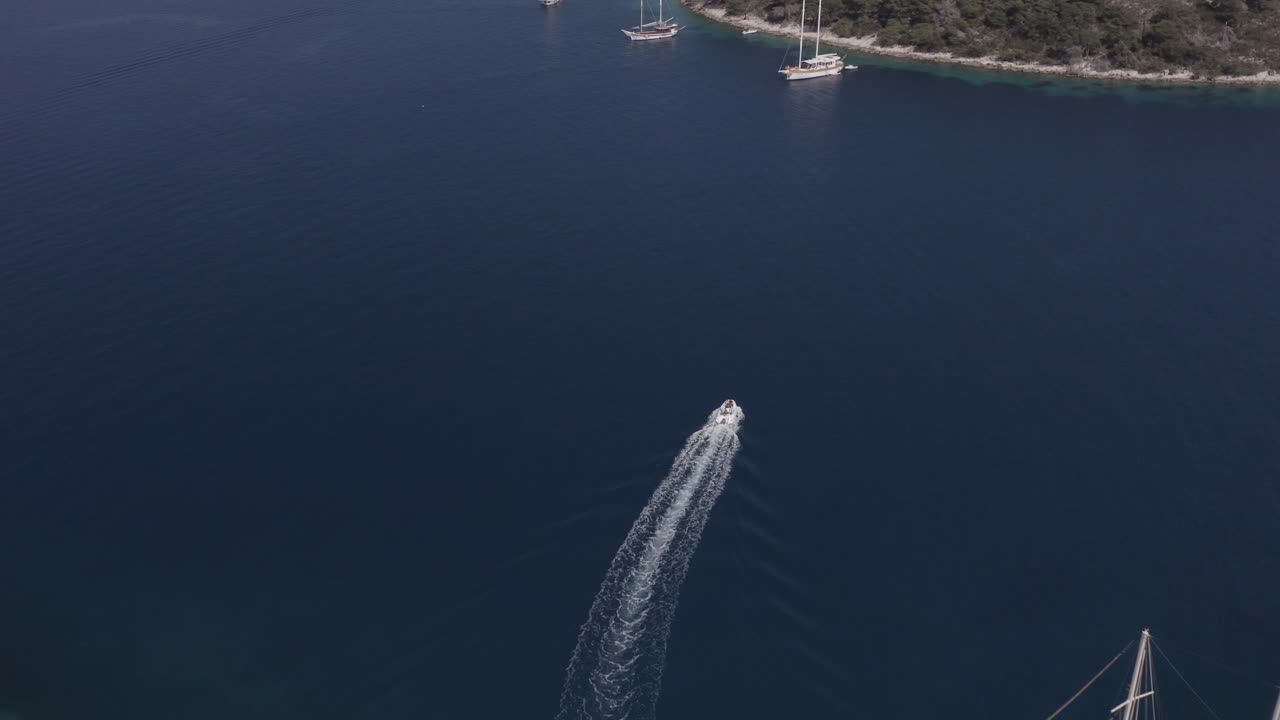 드론이 크리스탈처럼 은 바다에서 작은  배를 따라갑니다.