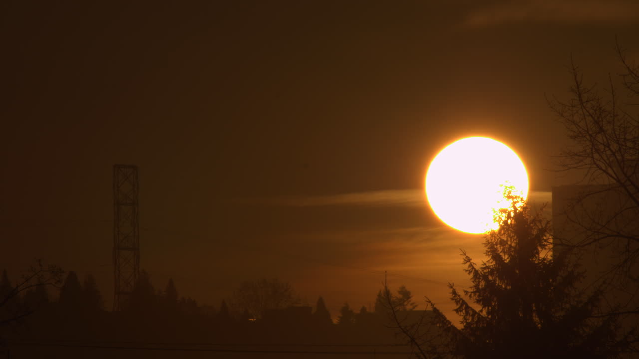 яркое солнце медленно поднимается вверх, просвечивая сквозь облака на рассвете - статичный кадр
