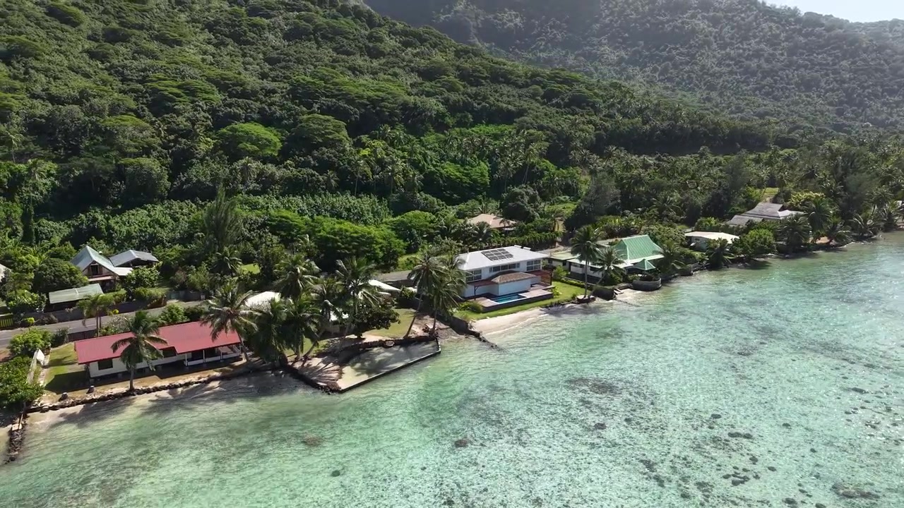 Drone Shot of Moorea Island, French Polynesia. Coastal Road Traffic, Homes and Green Hills