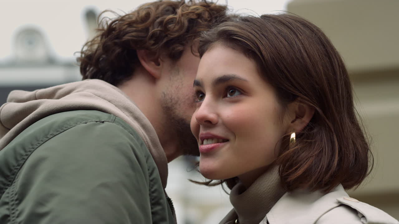 love couple feeling happy outdoor. Man whispering to woman ear on urban street.