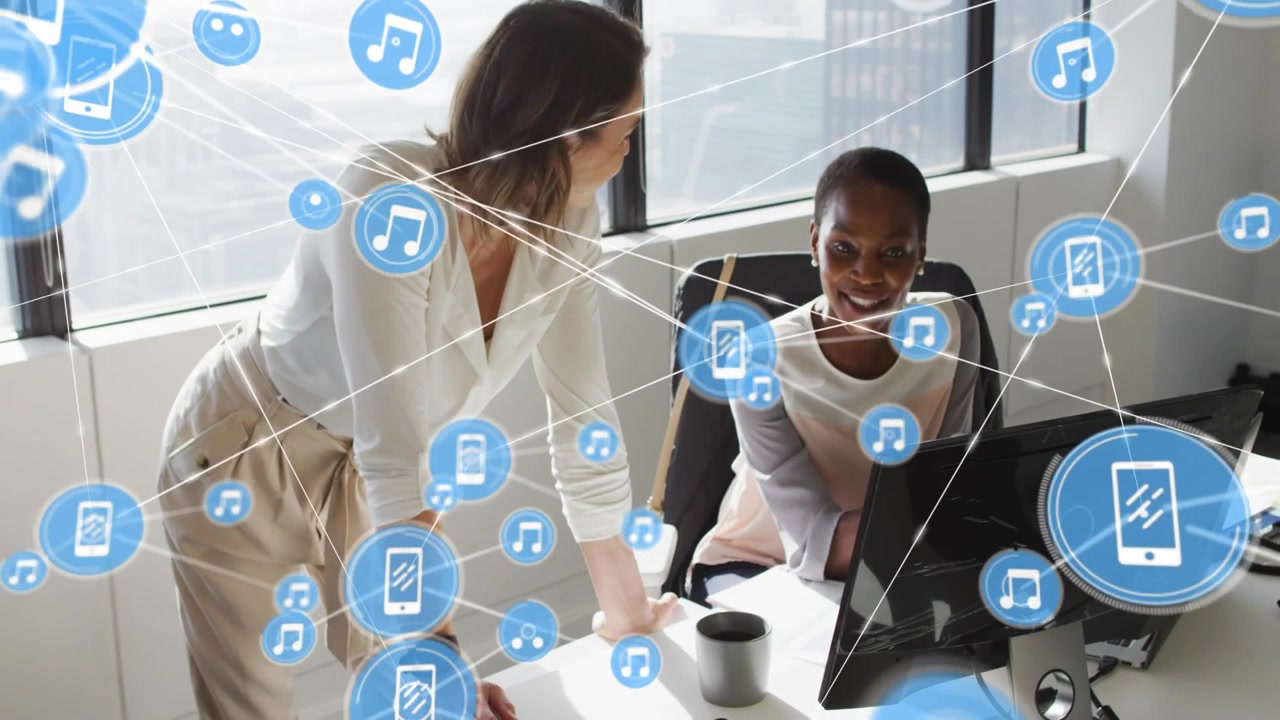 Mentor leaning at desk pointing at monitor, causing blue icons forming network for collaboration