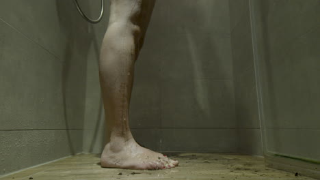 dirty female feet standing in a running shower stall