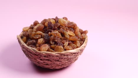 close-up of a bowl of raisins on a pink background