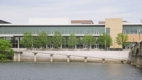 panning shot of a river flowing through a developed, downtown with a bridge