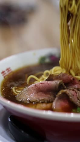 persona comiendo ramen con palillos de un cuenco