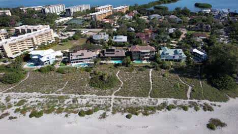 Drone-clip-moving-towards-beachfront-properties-on-bright-sunny-day-in-Sarasota,-Florida,-then-panning-down