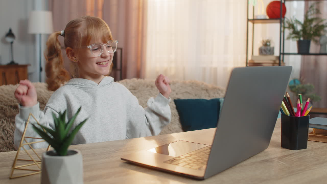 Young girl learning programming on laptop celebrating in excitement after achieving study success