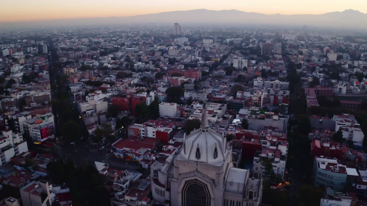 amplias tomas de drones del enorme estado de jesús que se elevan sobre la ciudad de méxico al atardecer, con la parroquia del purismo corazon de maria y calles rectas en el fondo
