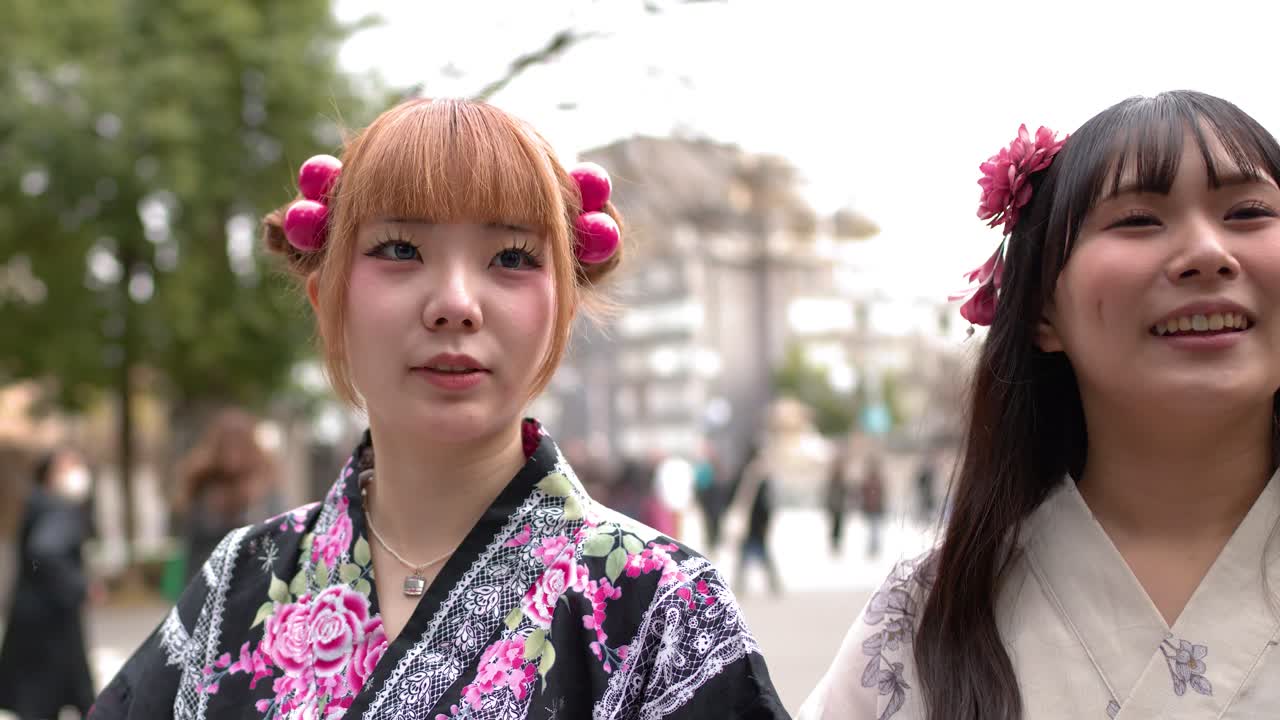 Due donne giapponesi che indossano yukata tradizionali camminano e parlano fuori dal santuario Meiji Jingu.