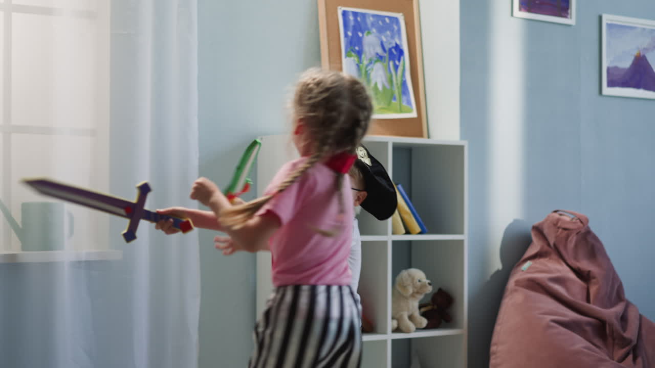 Couple of kids has fun playing with toy swords actively