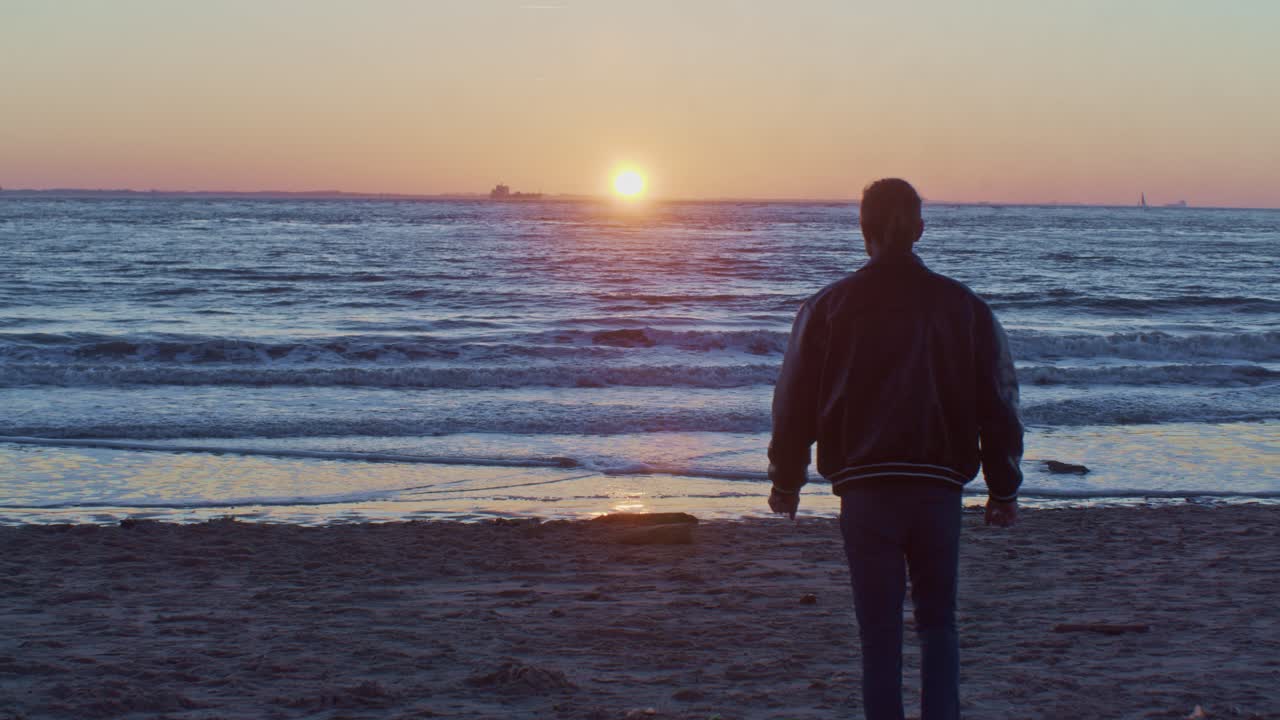 caucasian male man model walks on the beach near the sea ocean on the sand shore with sunset and cinematic actor's play