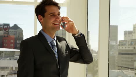 hombre de negocios mirando por su ventana hablando por teléfono