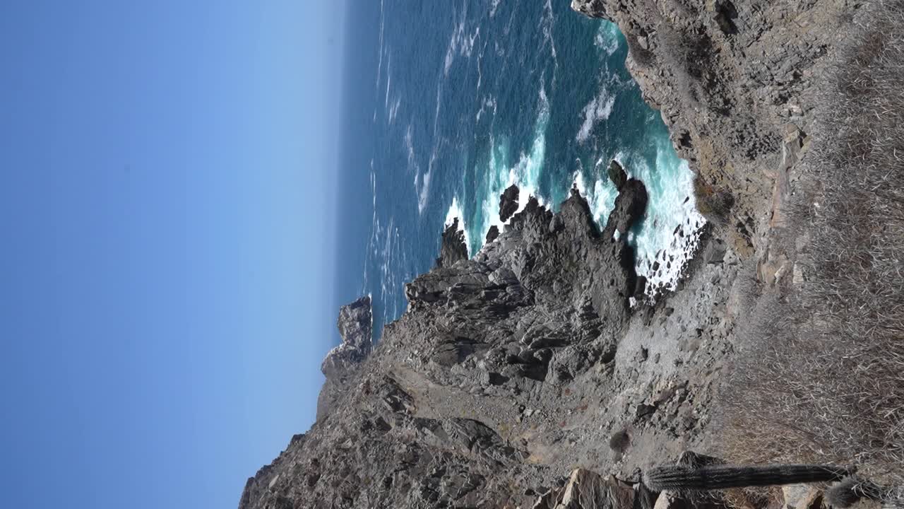 tomada vertical de punta lobos, olas que se estrellan contra acantilados rocosos en medio del día cerca de todos santos, bc, méxico